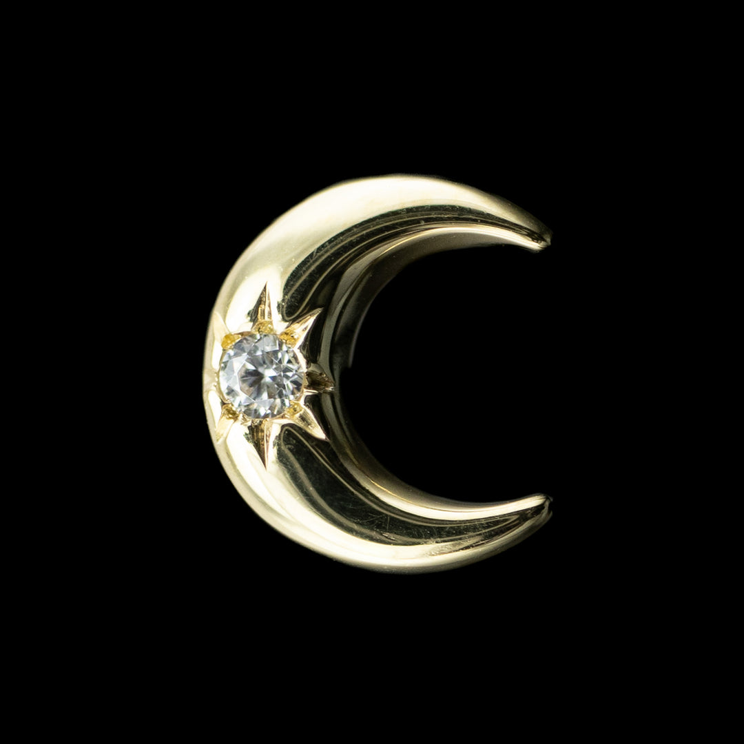 yellow gold body jewelry in the shape of a moon with a white cubic zirconia center. 